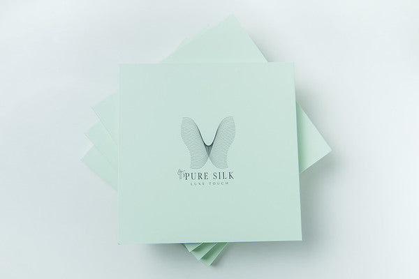 mint square boxes with it's pure silk logo stacked in a pile of four to form a star shape